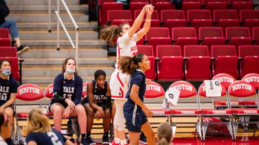 Emily Esposito shoots a three-pointer over a Yale defender in front of the Bulldog bench.