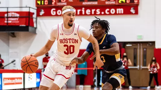 Javante McCoy brings the ball up the court with a Merrimack defender on his left.