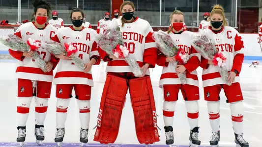 Nara Elia, Kristina Schuler, Corinne Schroeder, Rachel Allen and Jesse Compher all holding flowers as they stand on the blue line