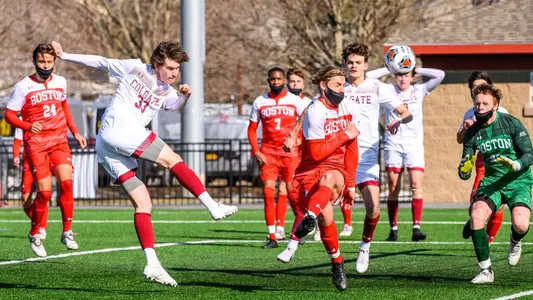 Colgate player fires a shot right of the goal with a defender in front of him as the goalkeeper Andrew Wike tries to protect the near post.