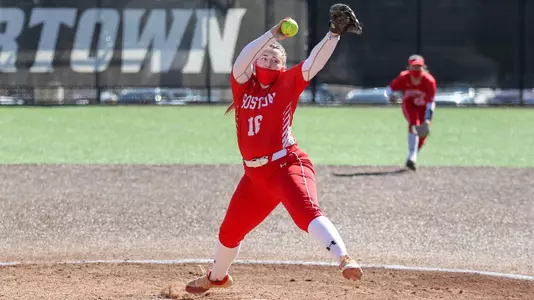 Ali DuBois has the ball over her head as the is halfway through her pitching motion looking toward home plate.