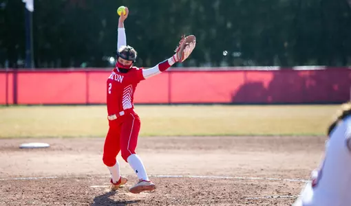 Emily Gant has the ball raised over her head as she goes through her windup pitching motion toward home palte.