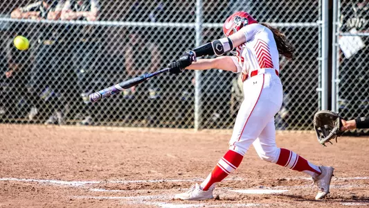 Nicole Amodio smashes a ball batting right handed at home plate with the bat pointed toward center on her swing.