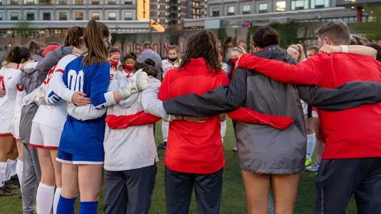 Members of the women's soccer team in a huddle prior to the start of the game