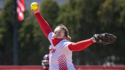 Ali DuBois is in her pitching windup during a pitch toward home plate.