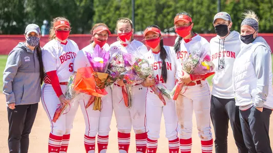 Boston University softball team's five seniors gathered for a photo with the three-member coaching staff. The seniors are holding flowers.