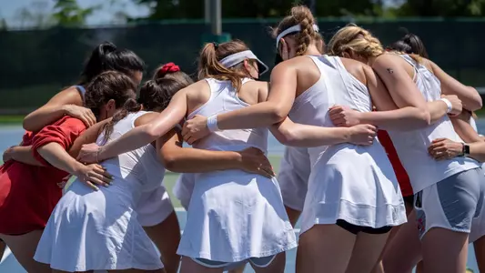 The Boston University women's tennis team huddles on the court before a match.