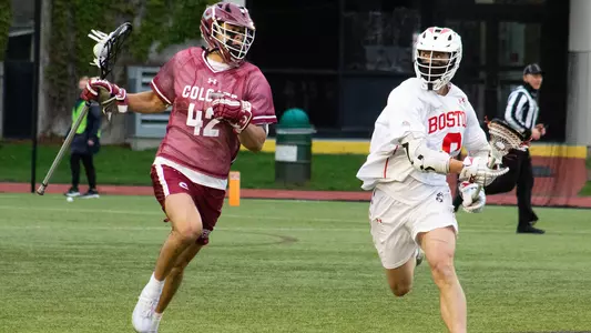 A Colgate men's lacrosse player runs away from a BU men's lacrosse player