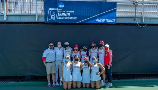 The members of the women's tennis team posing under an NCAA banner