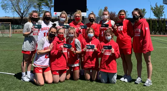 Members of the women's lacrosse team posing for a photo with their community service stickers