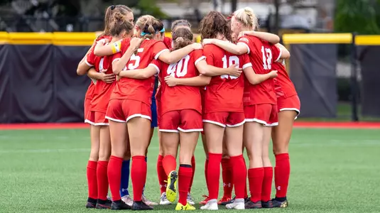 Women's soccer team starters in a huddle before the start of the match