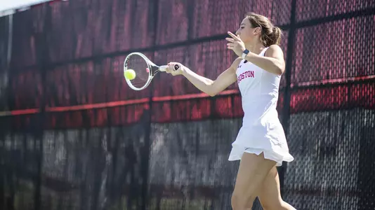 Erica Di Battista makes contact with a tennis ball on a forehand swing with her racquet.