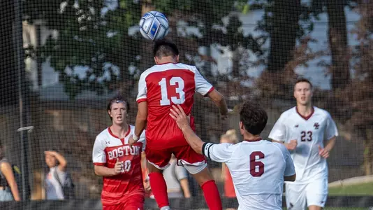 Matthew Boberg heads the ball up in the air with multiple players around him, including BC defender who has a hand on his back.