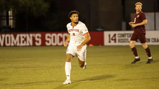 Ronaldo Marshall runs in the middle of the field with a UMass defender behind him.