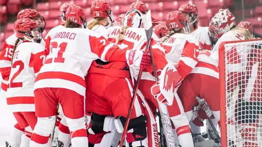 The women's hockey team huddles at their net before a game