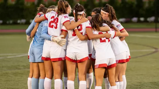 The women's soccer team huddles on the field before a match