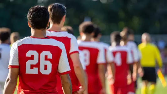 Members of the Boston University men's soccer team walk toward the middle of the field for the starting lineup and national anthem.