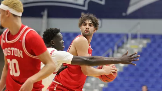 Sukhmail Mathon looks to pass the ball with a defender stretching arm out to side to guard against the pass