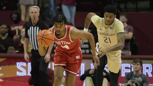 Miles Brewster drives the ball down the court with a Florida State defender behind him.