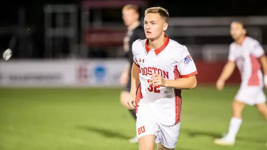 Andrew Rent is running across the field toward the soccer ball.