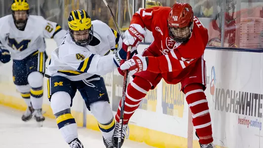 Luke Tuch battling for a puck against a Michigan player