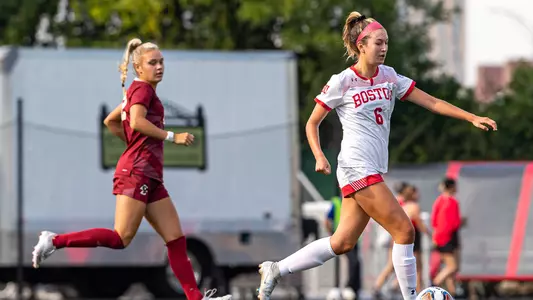 Photo of women's soccer senior Sophia Woodland dribbling the ball past a Boston College defender.