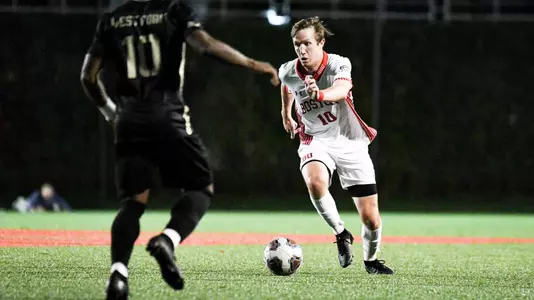 Colin Innes dribbles the ball up the field with an Army defender in front.