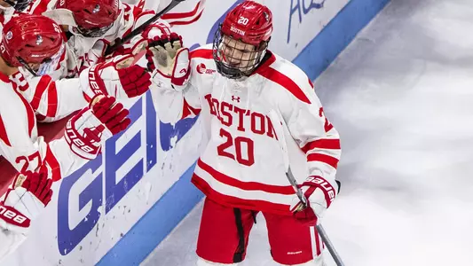 Lane Hutson high-fiving his teammates as he skates by the BU bench after scoring a goal
