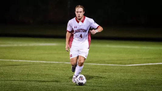 Neal Carlson dribbles the soccer ball up the field on a rainy night.