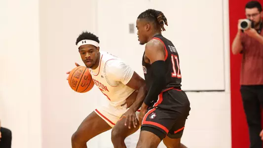 Walter Whyte backs down a Northeastern defender toward the hoop with the ball in his hands.
