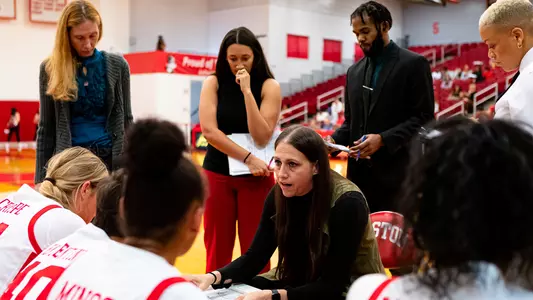 Photo of the women's basketball team huddling up and discussing a play.