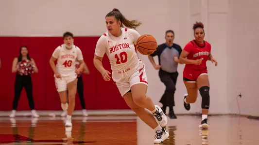 Photo of women's basketball sophomore Alex Giannaros dribbling up the court against Northeastern.