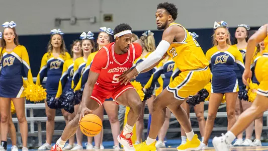 Walter Whyte bounces the ball trying to back down a Merrimack defender guarding the hoop