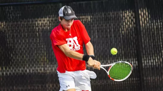 Adiran Pawlowski uses a double backhand to hit a tennis ball back