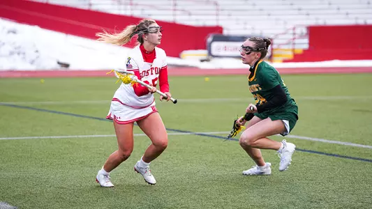 Caroline Pinho holds the ball while a Vermont defender looks on.