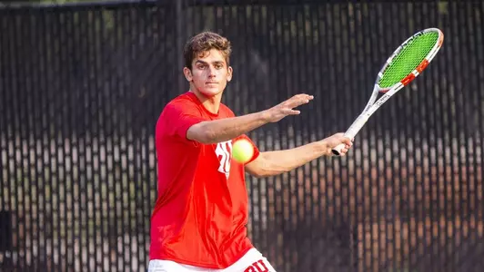 Jonah Dickson has his forehand back waiting for the tennis ball to approach.