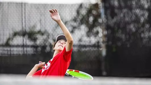 Johann Sojanz has the racquet pulled down like a slingshot awaiting a high tennis ball to come toward him.