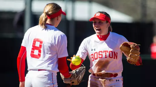 Caitlin Coker hands the ball to pitcher Allison Boaz in the circle.
