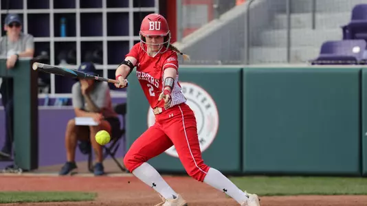 Emily Gant makes contact with the ball at home plate, slapping it down the third base line.