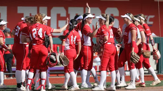 BU Softball team high fives one another near the dugout.