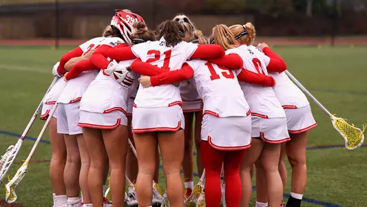 Photo of the women's lacrosse team huddling before a game.