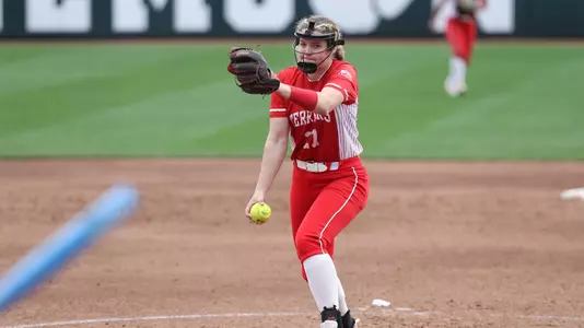 Lizzy Avery is in the middle of her pitching windup toward home plate.