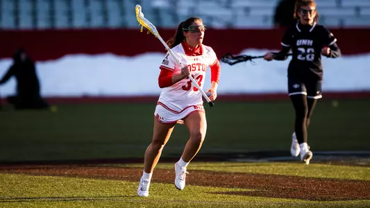Teagan Lucchese runs with a ball while a UNH defender watches in the background.