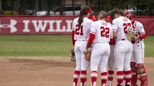 The BU Softball infielders gather in the pitcher's circle for a huddle.