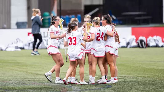 Photo of the women's lacrosse team huddling following a goal.