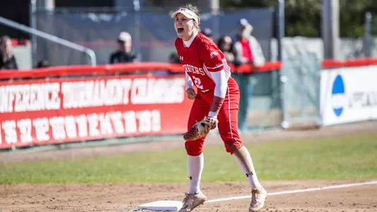 Caitlin Coker jumps up and screams at third base after the team gets an out.