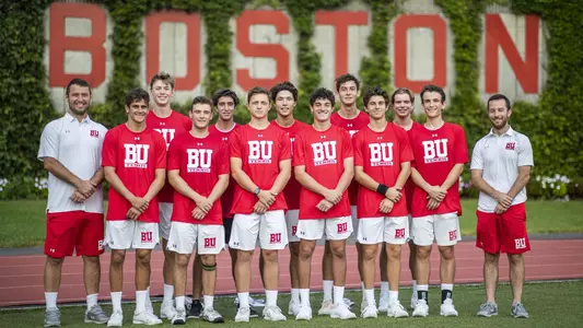 2021-22 Boston University men's tennis team poses for a photo in front of the ivy wall with Boston spelled out in large letters.