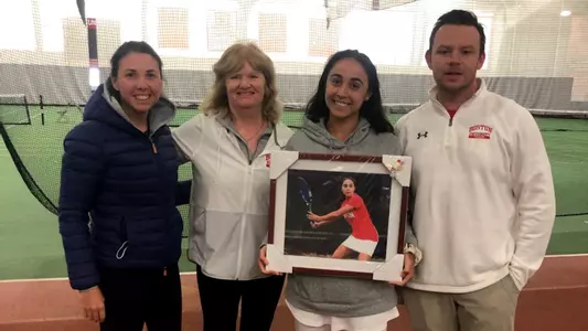 Shelly Yaloz poses for a photo with the BU women's tennis staff while also holding a framed action photo.