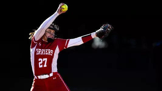 Lizzy Avery is in the middle of her pitching windup toward home plate.
