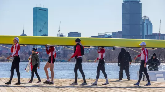 BU men's rowing carrying an eight boat on the dock into the DeWolfe Boathouse